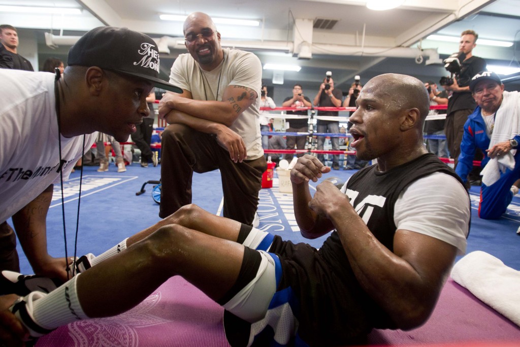 DeJuan Blake helps boxer Floyd Mayweather Jr. of the U.S. with sit-ups as Leonard Ellerbe, CEO of Mayweather Promotions, looks on in Las Vegas